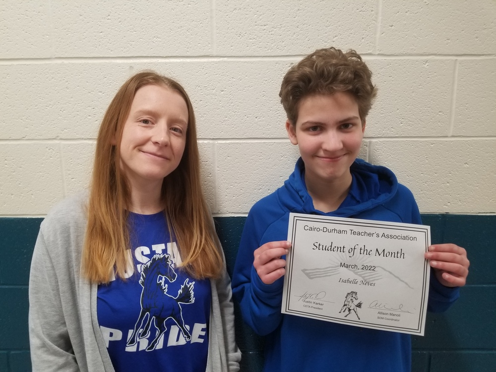 Mrs. Goodwin wearing a blue Mustang Pride shirt (left) and student Isabelle Neves (right) wearing a blue sweatshirt and holding a certificate