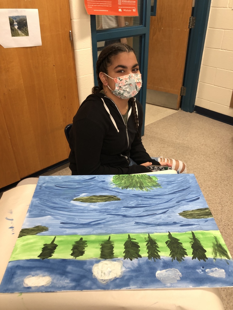 middle school girl seated at a desk with her landscape painting