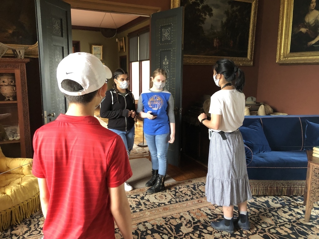 three middle school students with a tour guide inside a local historical site