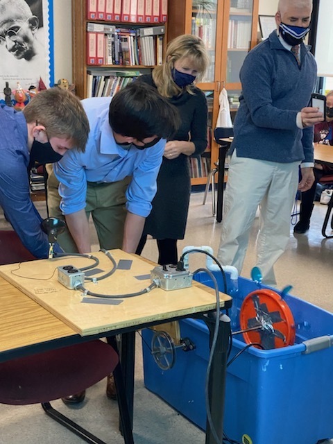 two high school students demonstrate hydroelectricity for two faculty judges