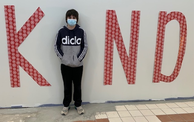 A student standing between the letters K, N, and D to spell out KIND