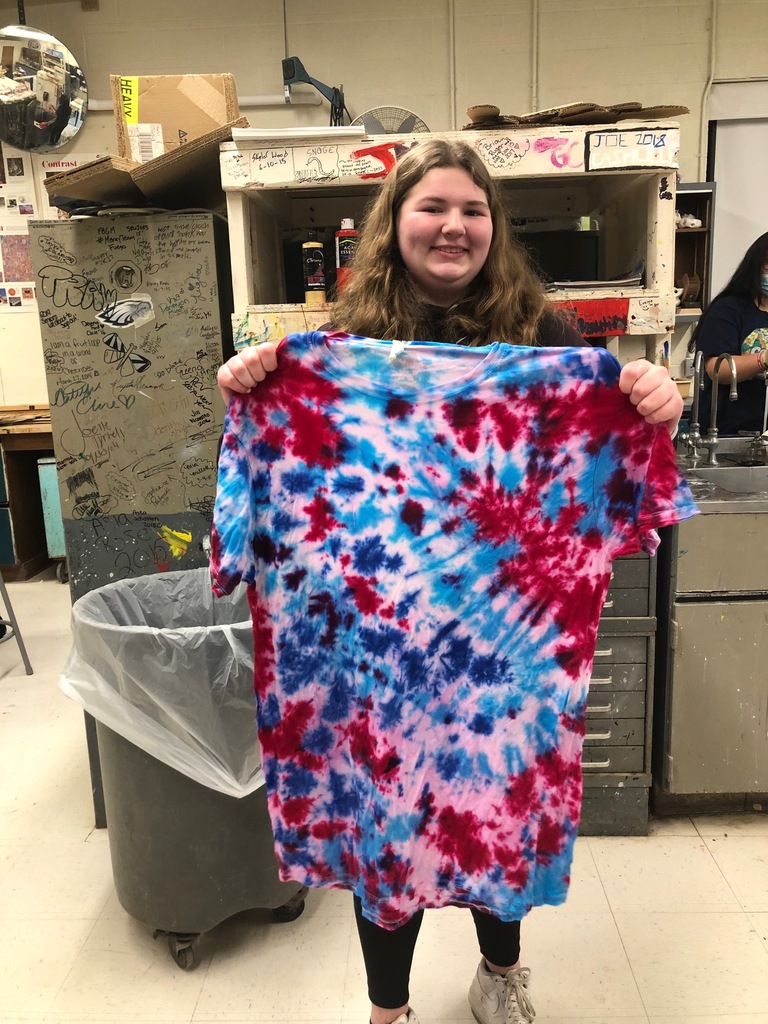 a female student holds up a red, purple and blue tie-dyed t-shirt