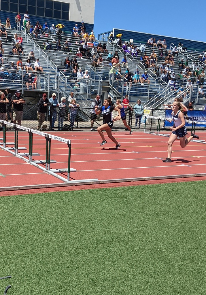 high school track athletes running a hurdle event