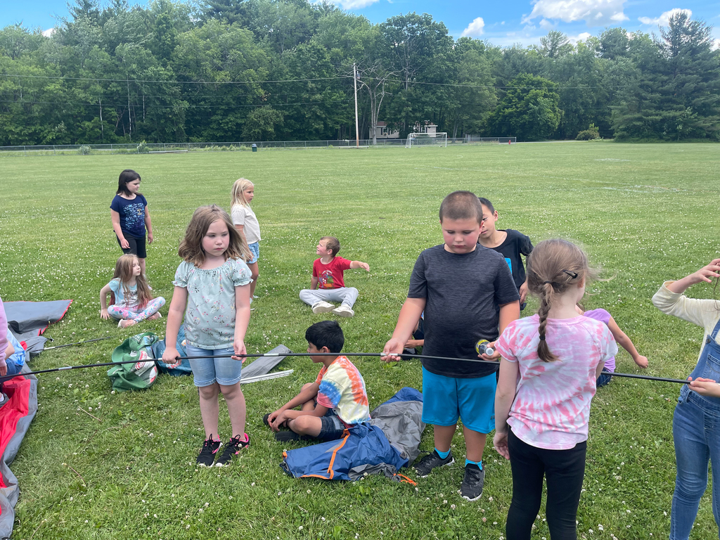 first grade students outdoors holding tent poles